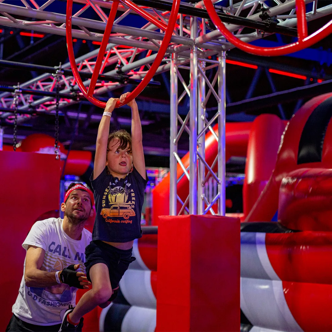 parent helping child across ninja warrior course