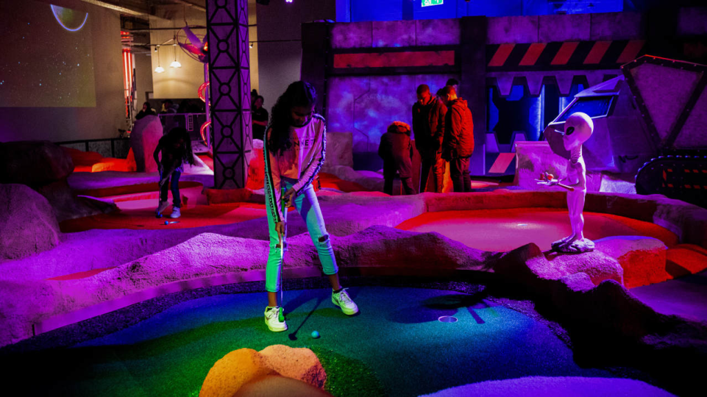 indoor crazy golf course with leds and woman putting at Mr Mulligans